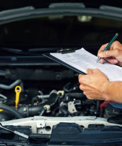 car maintenance and repair - mechanic writing checklist paper on clipboard